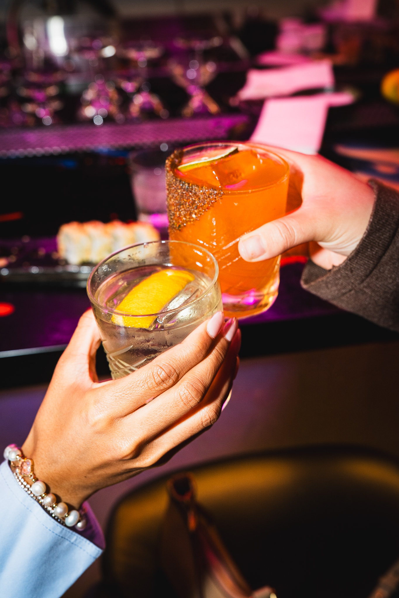 Cloak & Petal craft cocktails — two guests clinking glasses at the bar, San Diego
